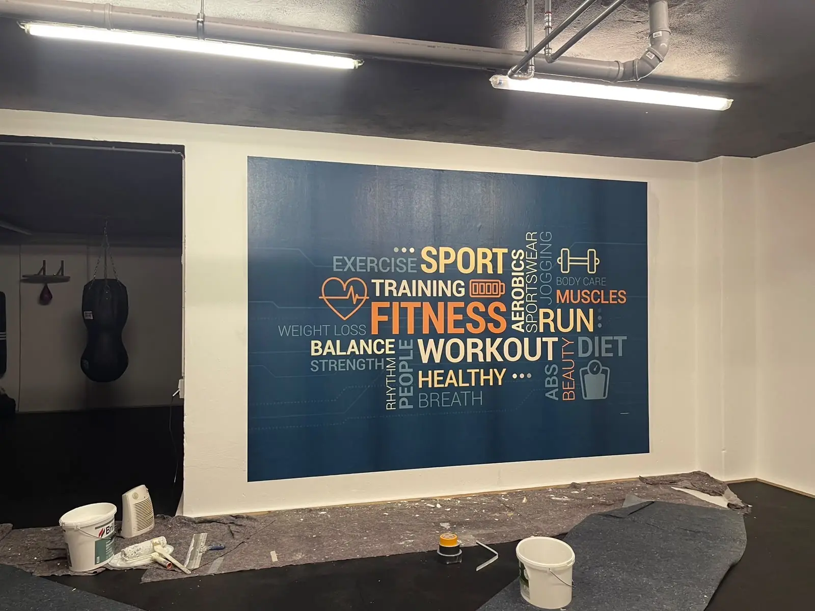 Großflächiges Wandbild mit Fitness-Motiven in einem Trainingsraum